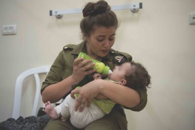 IDF soldier cradles a small child with a bottle