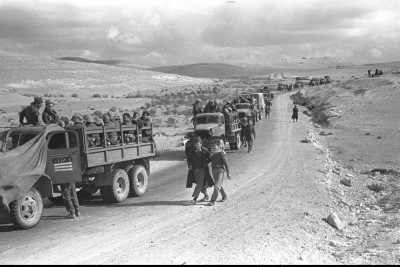 A convoy of military trucks drives down a dirt road in the Negev, 1948 