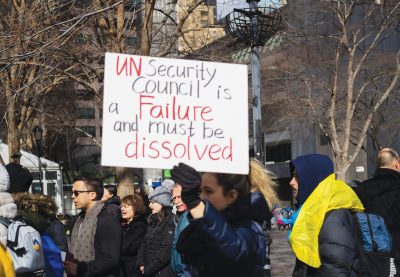 A woman holds a sign that reads 'UN Security Council is a Failure and must be dissolved'